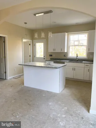 a large kitchen with granite countertop a sink and white cabinets