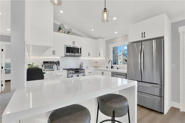 a kitchen with stainless steel appliances granite countertop a refrigerator a stove a sink a microwave a dining table and chairs