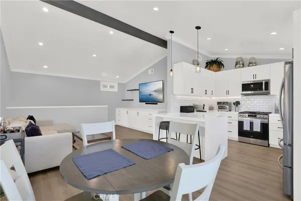 a kitchen with stainless steel appliances kitchen island granite countertop a dining table chairs sink refrigerator and cabinets