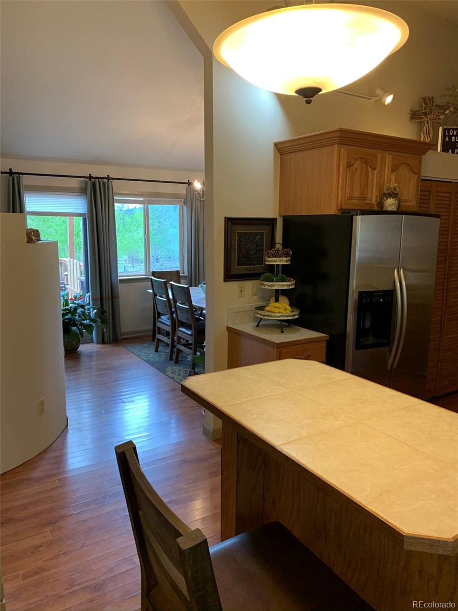 161 Saddlestring Road Bailey, CO 80421 - Photo 8 of 32 a kitchen with stainless steel appliances wooden floor dining table and chairs