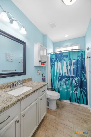 a bathroom with a granite countertop sink a toilet a mirror and shower