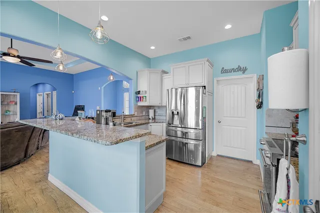 a kitchen with stainless steel appliances granite countertop a refrigerator a stove a sink dishwasher and a refrigerator with wooden floor