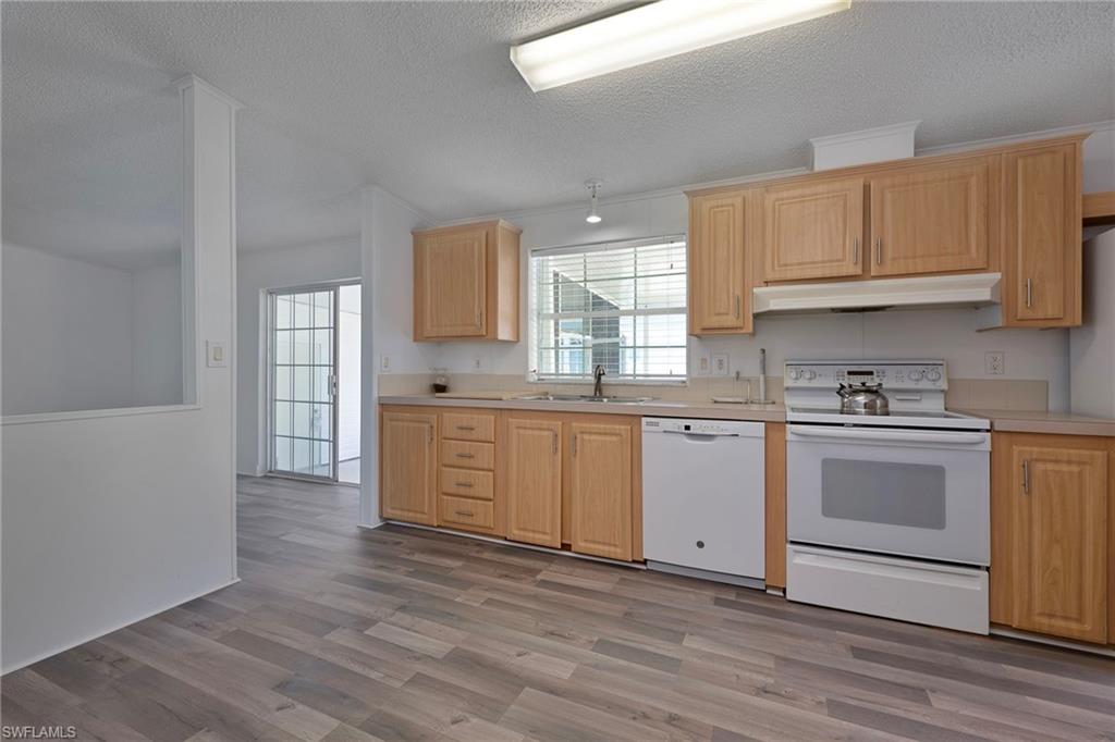 276 Grosbeak Lane, Unit 276 Naples, FL 34114 - Photo 5 of 13 a kitchen with granite countertop white cabinets and white appliances