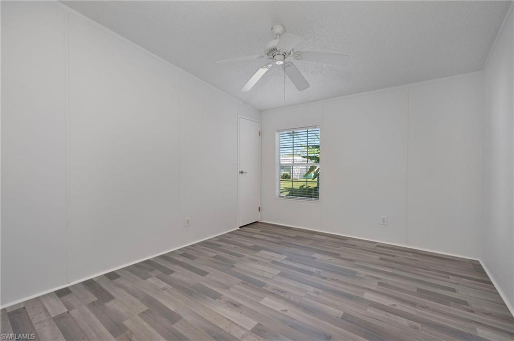 276 Grosbeak Lane, Unit 276 Naples, FL 34114 - Photo 9 of 13 wooden floor in an empty room with a window