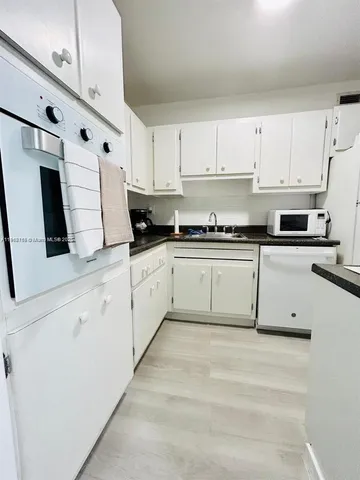 a white kitchen with stainless steel appliances granite countertop white cabinets a sink and dishwasher