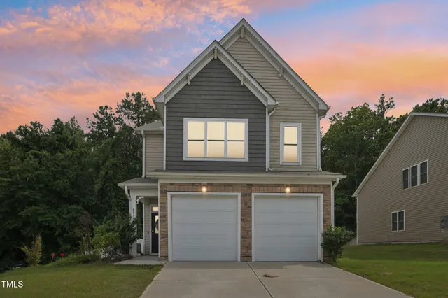 a front view of house with yard and trees in the background