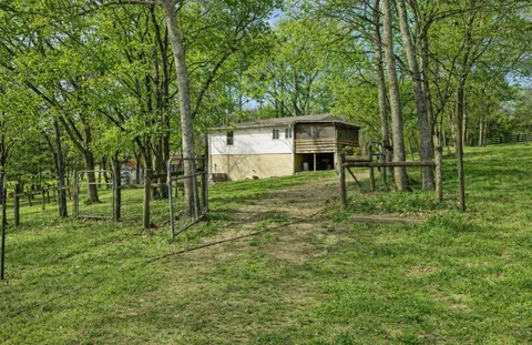 a view of a house with a big yard and large trees