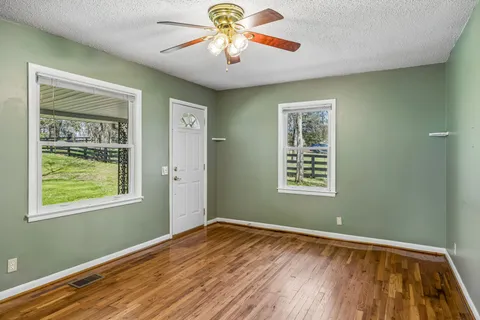a view of an empty room with window and wooden floor