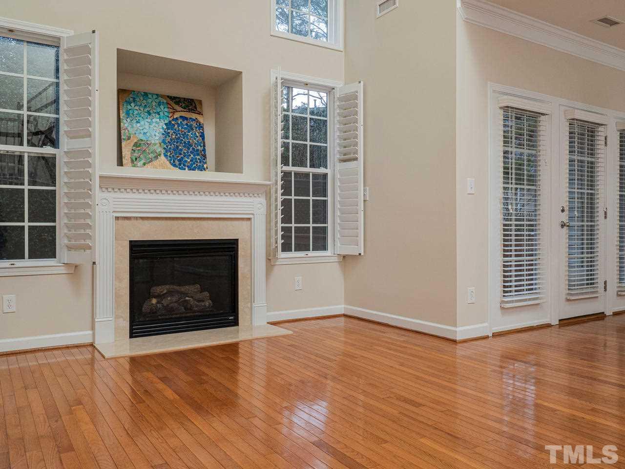 6025 Four Townes Lane Raleigh, NC 27616 - Photo 13 of 24 an empty room with wooden floor a fireplace and windows