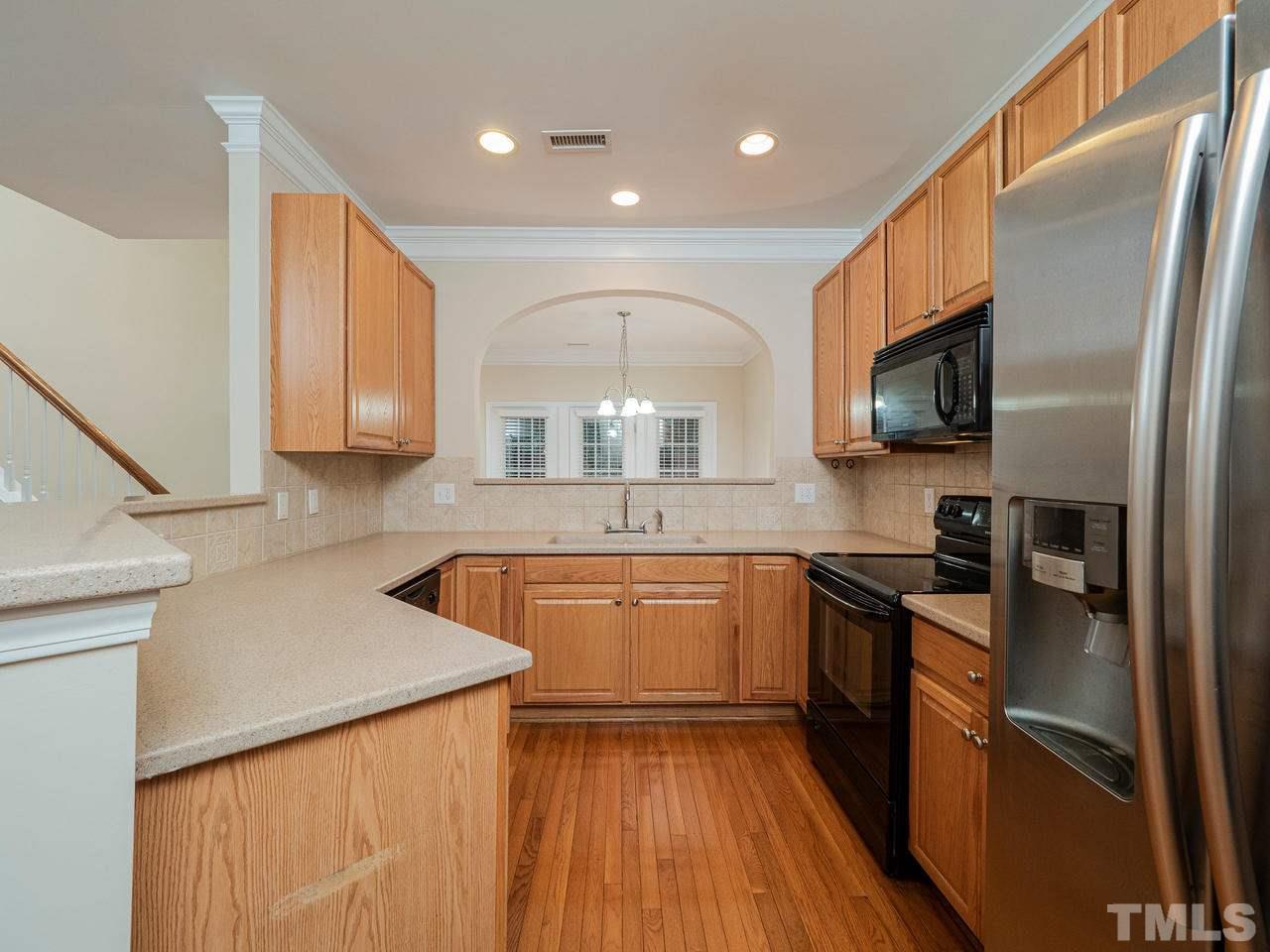 6025 Four Townes Lane Raleigh, NC 27616 - Photo 7 of 24 a kitchen with stainless steel appliances granite countertop a sink a stove top oven a refrigerator with wooden floors and granite countertops