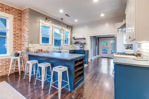 a large kitchen with kitchen island granite countertop a stove a sink a dining table and chairs