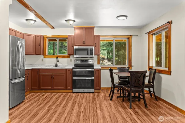 a open kitchen with stainless steel appliances granite countertop a stove top oven a dining table and chairs with wooden floor