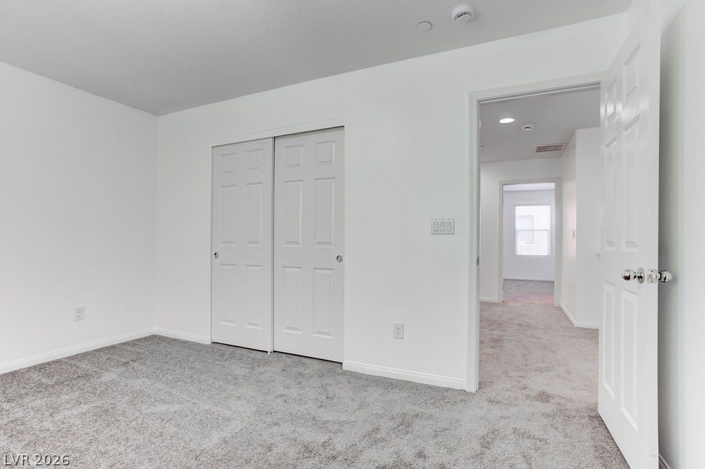 4650 Ranch House Road, Unit 47 North Las Vegas, NV 89031 - Photo 20 of 43 A well-lit bedroom features plush gray carpeting and a practical bi-fold closet, offering comfort and convenience.