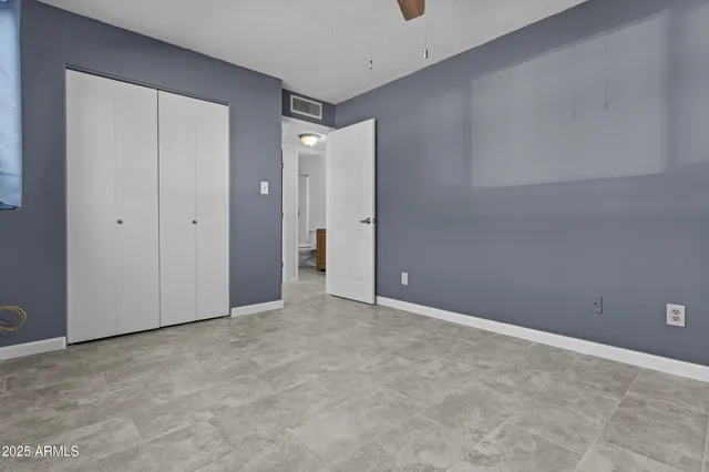 an empty room with windows and fan