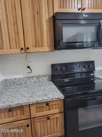 a kitchen with granite countertop white cabinets and black appliances