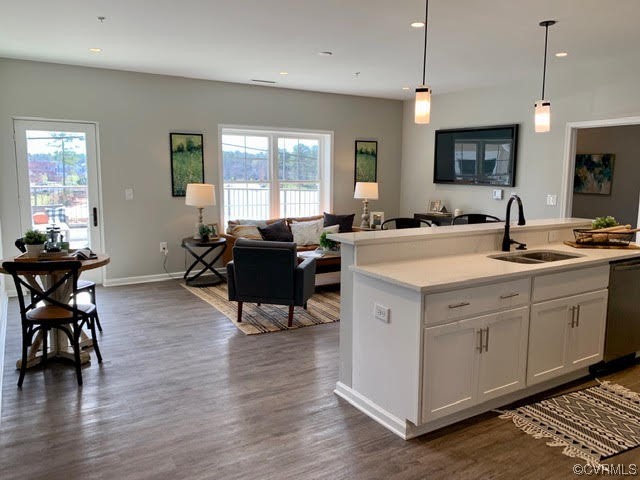 a open kitchen with stainless steel appliances granite countertop a stove a sink a dining table and chairs with wooden floor