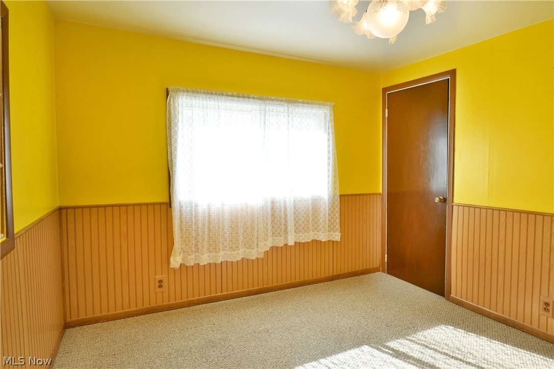 878 Ridge Road Vienna, OH 44473 - Photo 42 of 50 Empty room with a wainscoted wall, carpet floors, and hanging lights