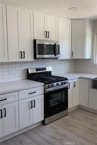 a kitchen with stainless steel appliances granite countertop a stove a sink and white cabinets