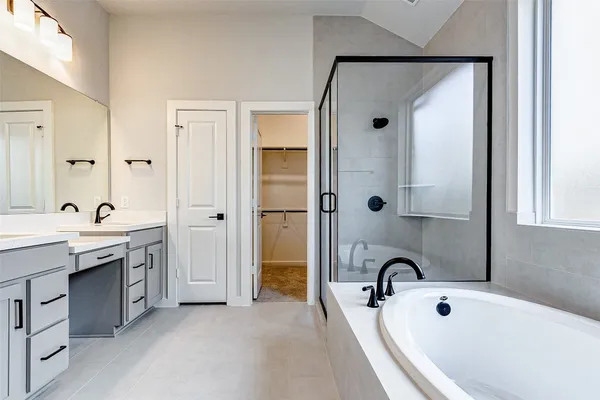 a bathroom with a tub sink double vanity and mirror