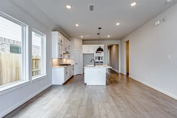 a large kitchen with stainless steel appliances a large center island wooden floor and a large window