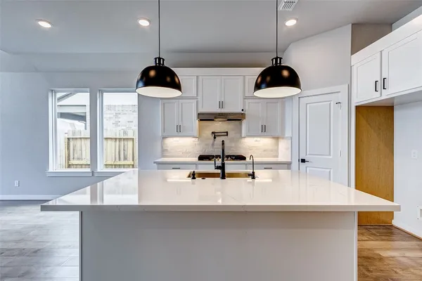 a kitchen with stainless steel appliances a sink a stove a dining table and chairs with wooden floor