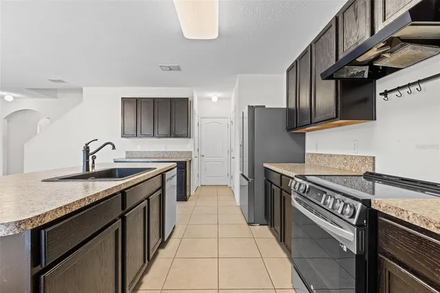 a kitchen with granite countertop a refrigerator stove and sink