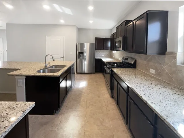 a kitchen with stainless steel appliances granite countertop a sink and a refrigerator