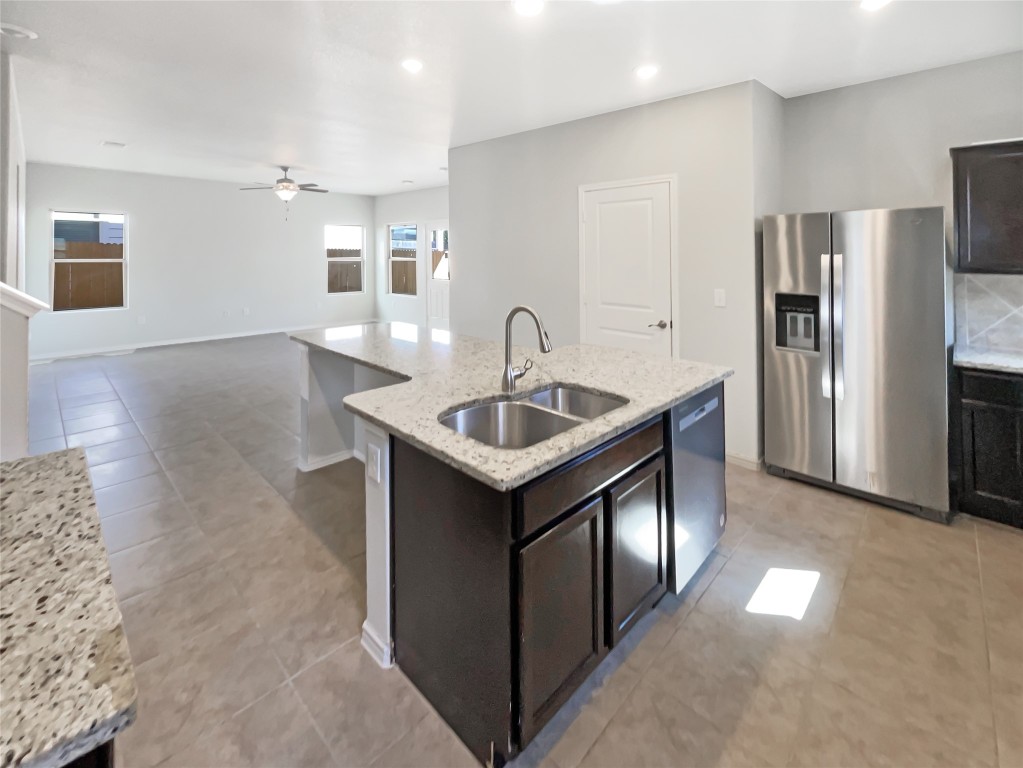 5709 Southerner Way Austin, TX 78747 - Photo 25 of 26 Kitchen featuring stainless steel appliances, a center island with sink, ceiling fan, light stone countertops, and light tile patterned floors