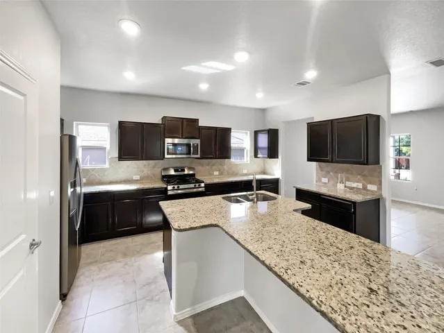a large kitchen with a large counter top stainless steel appliances and cabinets