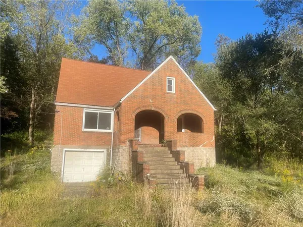 a backyard of a house with large trees and plants