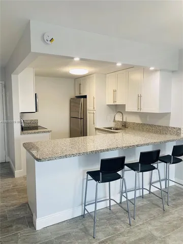 a kitchen with granite countertop kitchen island a table and chairs in it