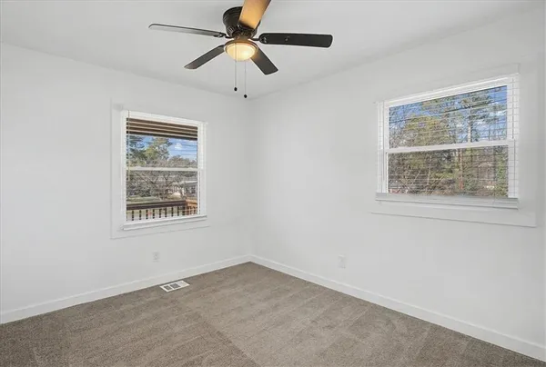an empty room with a window and a fan