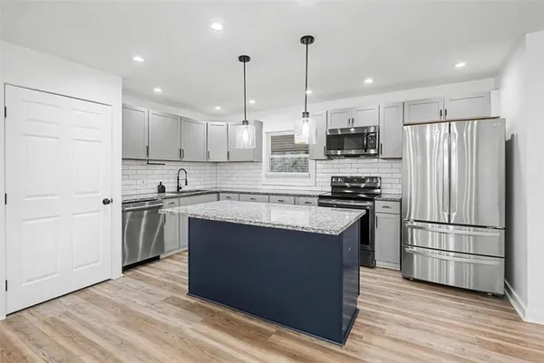 a kitchen with stainless steel appliances granite countertop a refrigerator a stove a sink and a oven