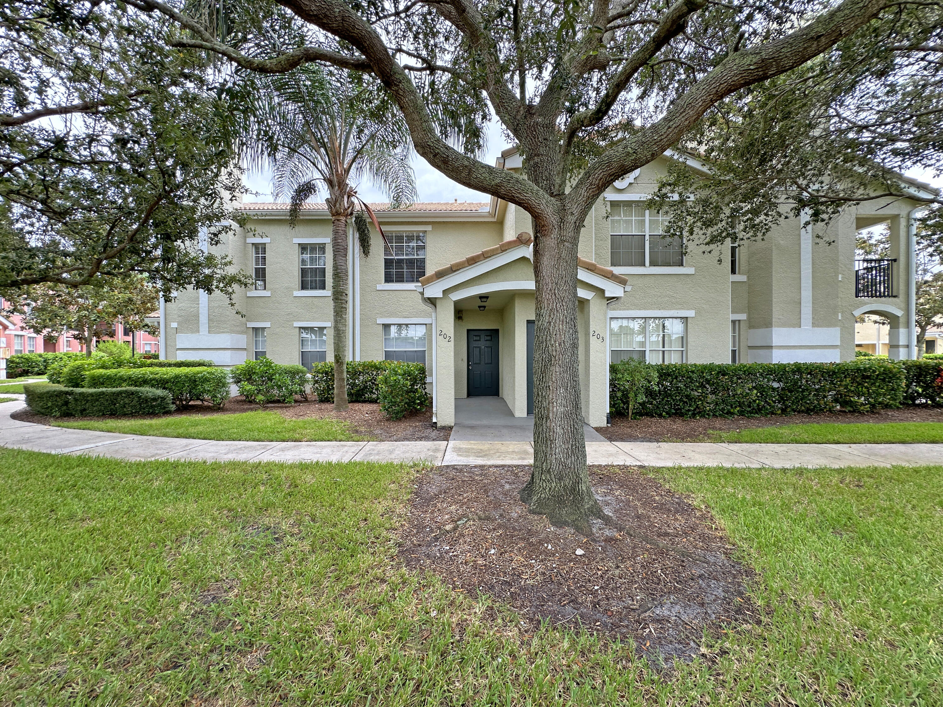 166 Southwest Peacock Boulevard, Unit 34202 Port St. Lucie, FL 34986 - Photo 2 of 56 a front view of a house with a yard and garage