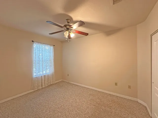 an empty room with a window and a fan