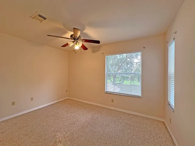 an empty room with closet and a chandelier fan
