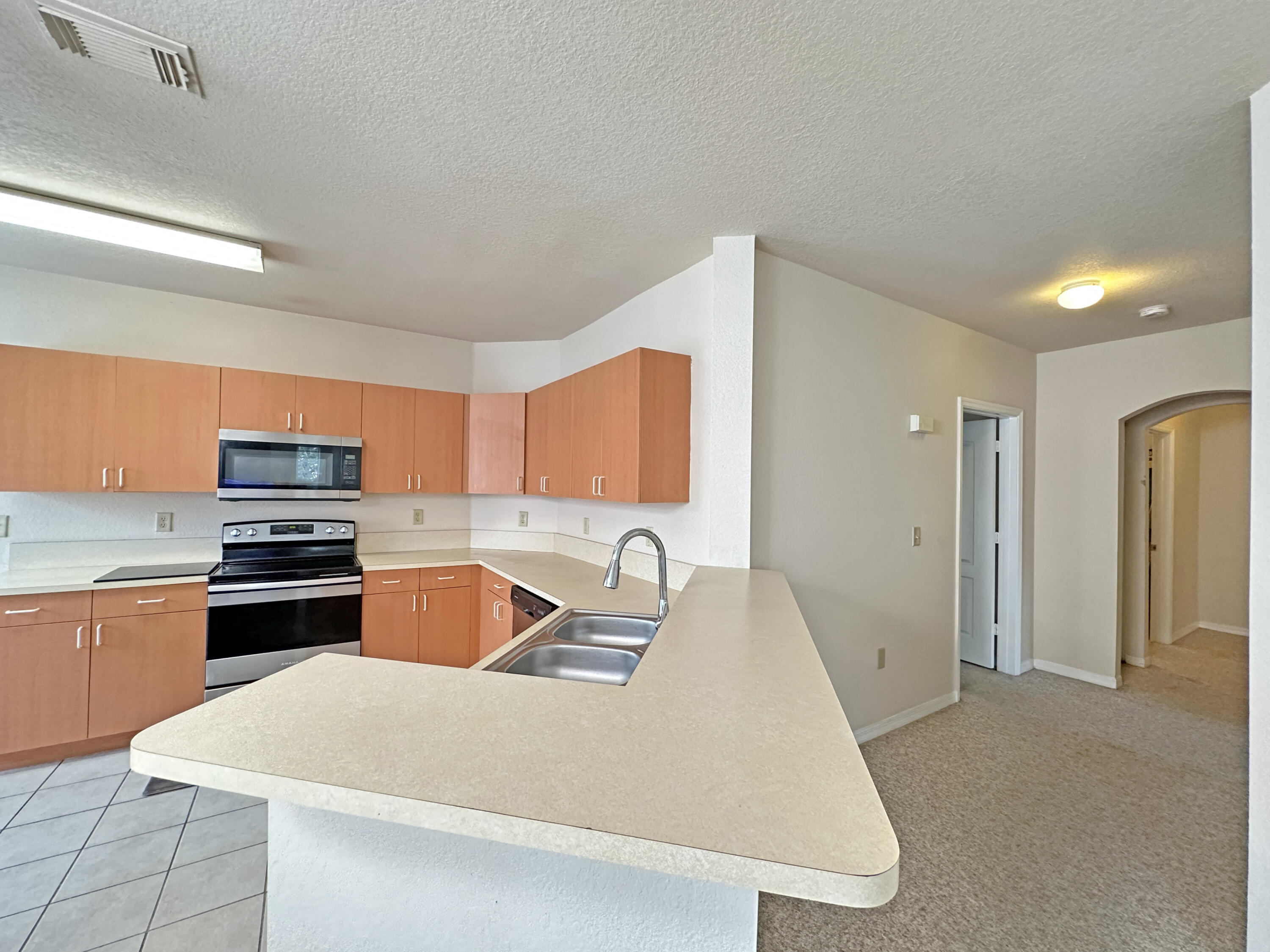 166 Southwest Peacock Boulevard, Unit 34202 Port St. Lucie, FL 34986 - Photo 9 of 56 a kitchen with stainless steel appliances granite countertop a sink stove and refrigerator