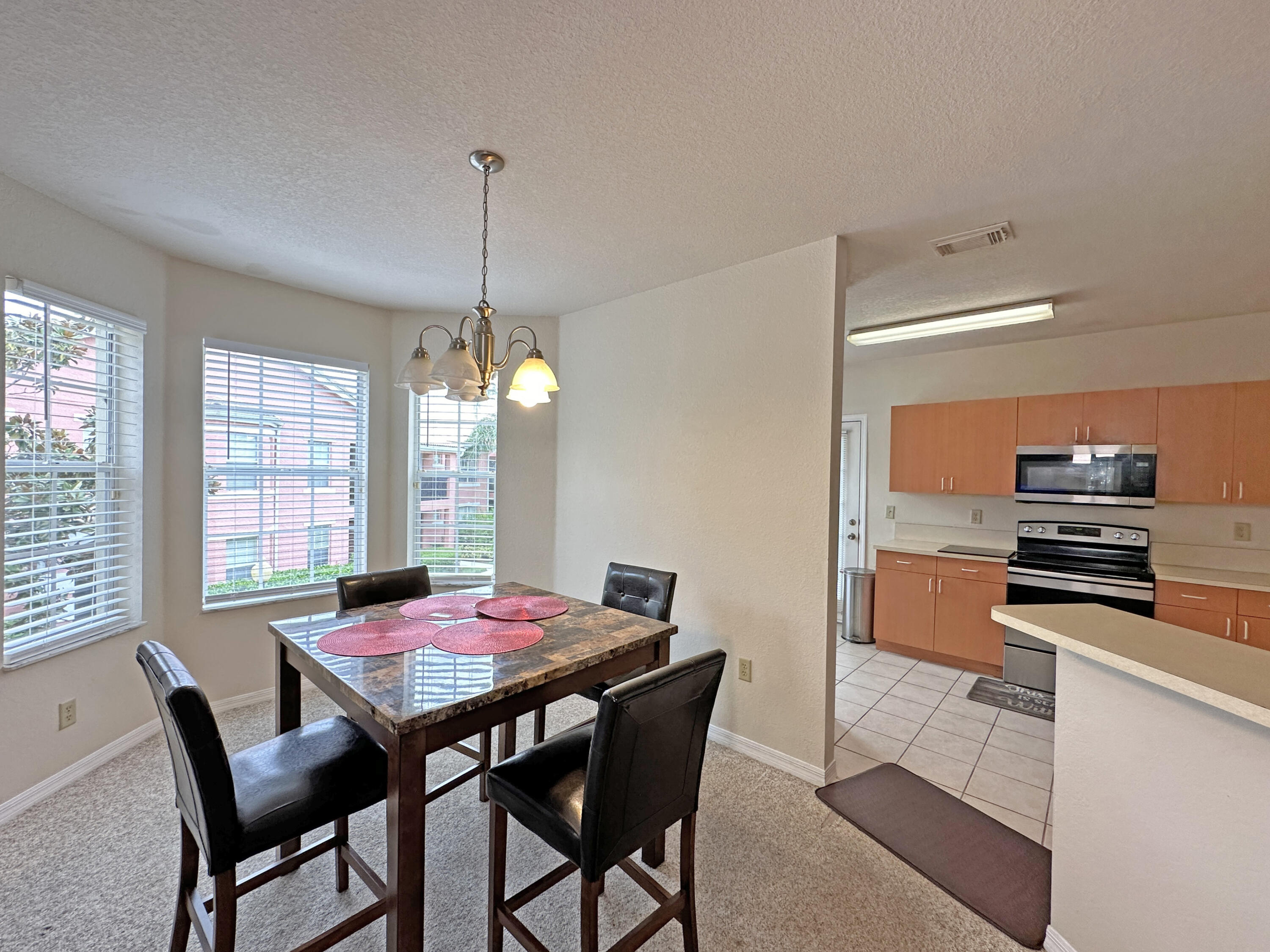 166 Southwest Peacock Boulevard, Unit 34202 Port St. Lucie, FL 34986 - Photo 10 of 56 a kitchen with a dining table chairs and refrigerator