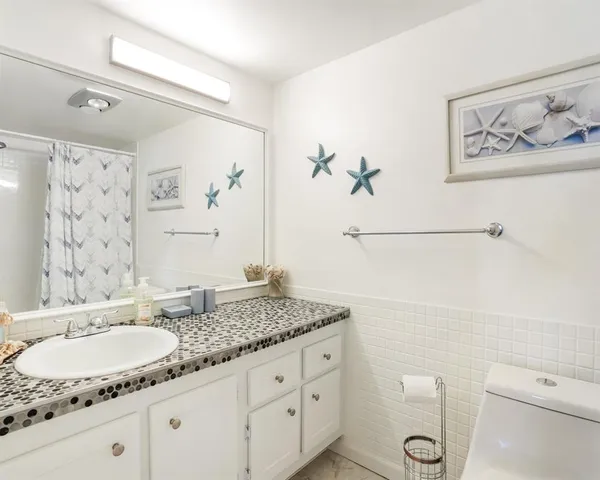 a bathroom with a granite countertop sink a toilet and a mirror