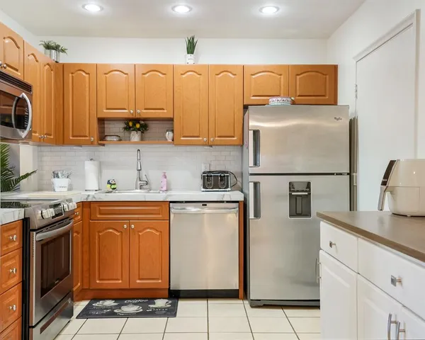a kitchen with stainless steel appliances granite countertop a refrigerator a stove a sink and white cabinets
