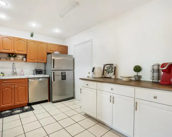 a kitchen with sink a refrigerator and white cabinets