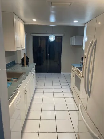 a kitchen with a sink a refrigerator and cabinets