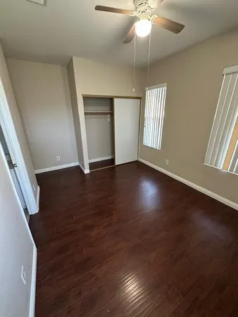 an empty room with wooden floor fan and windows