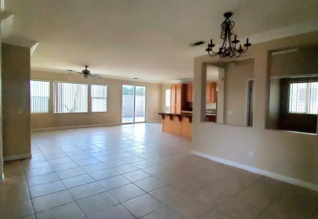 a view of a hallway with chandelier and dining area