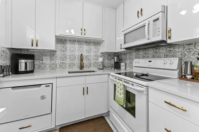 a kitchen with stainless steel appliances granite countertop a stove a sink and white cabinets