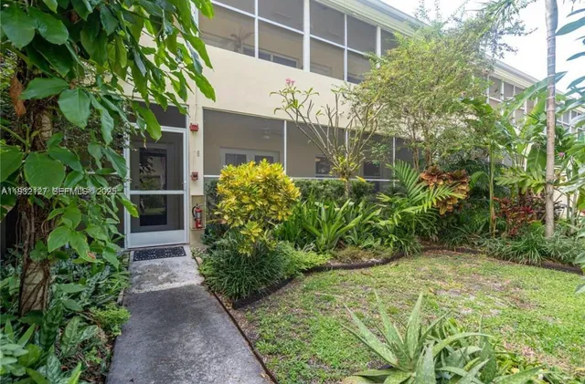 a view of a house with potted plants and large trees
