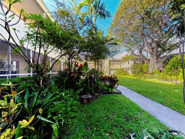 a view of house in front of a big yard with large trees