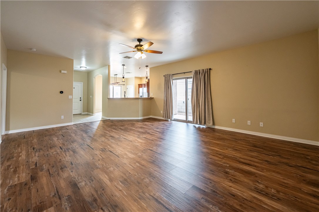 3546 North Kenneth Road Kingman, AZ 86409 - Photo 8 of 35 Spacious living area featuring wood-look flooring, a ceiling fan, and sliding glass doors with curtains