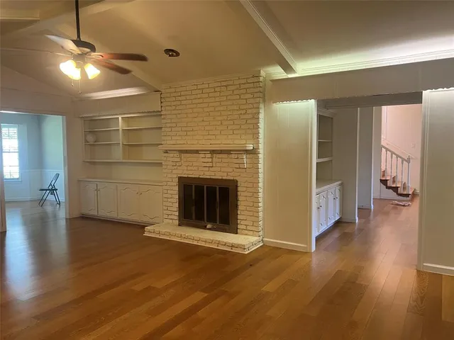 an empty room with wooden floor a fireplace and window
