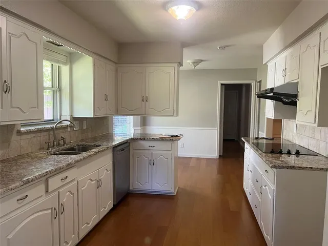 a kitchen with granite countertop cabinets stainless steel appliances a sink and a window